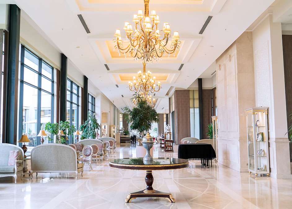 Luxurious London lounge with chandeliers, marble flooring, and classic furniture designed by Oraanj Interior Design.