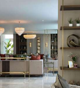 Elegant open-plan living room with plush seating, gold accents, and crystal chandeliers in Hornchurch by Oraanj Interior Design.