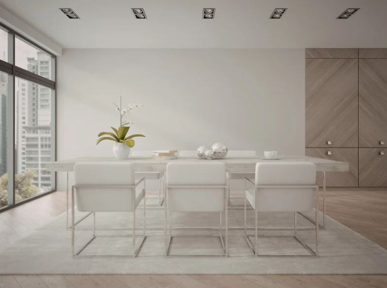 Minimalist dining area with white dining table, transparent chairs, neutral tones, and large window bringing in natural light.