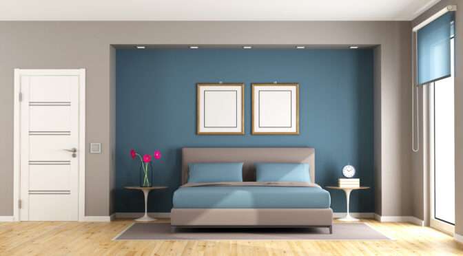 Modern bedroom with blue accent wall, grey walls, minimalist decor, and natural wood flooring.