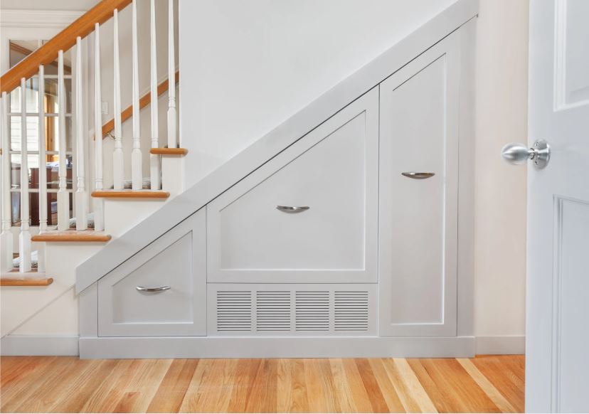 Built-in under-stair storage with panelled cabinetry, integrated handles, and a clean white finish in a modern home.