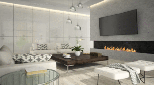 A modern living room with a wall-mounted television above a linear fireplace, neutral-toned seating, a low wooden coffee table, glass side table, pendant lighting, and soft ambient illumination.