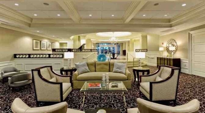 Modern hotel lobby with elegant furniture, coffered ceiling, and ambient lighting.
