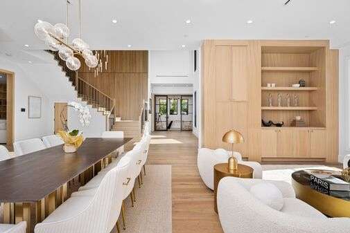 Neutral living and dining room with white chairs, wood finishes, gold accents, and modern decor.