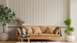 A cosy living room with a tan upholstered sofa, decorative cushions, a small side table with flowers, indoor plants in ceramic pots, and a light neutral wall with vertical panelling.