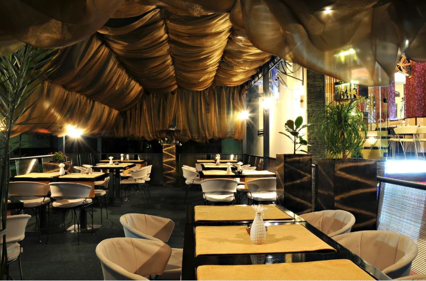 Stylish restaurant interior with draped ceiling, ambient lighting, modern dining tables, and an intimate, upscale atmosphere.