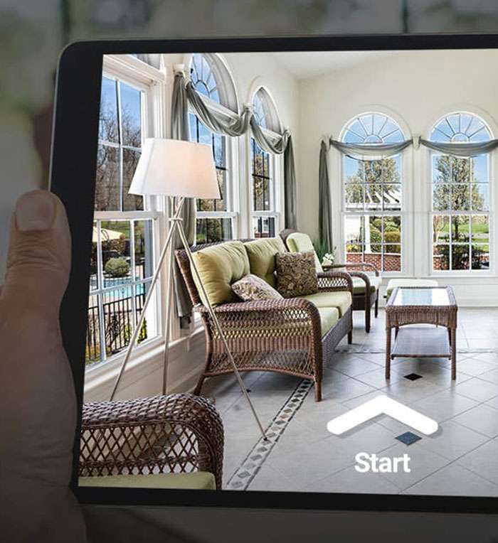 Hand holding tablet displaying augmented reality sunroom interior design with furniture Hand holding tablet displaying augmented reality sunroom interior design with furniture