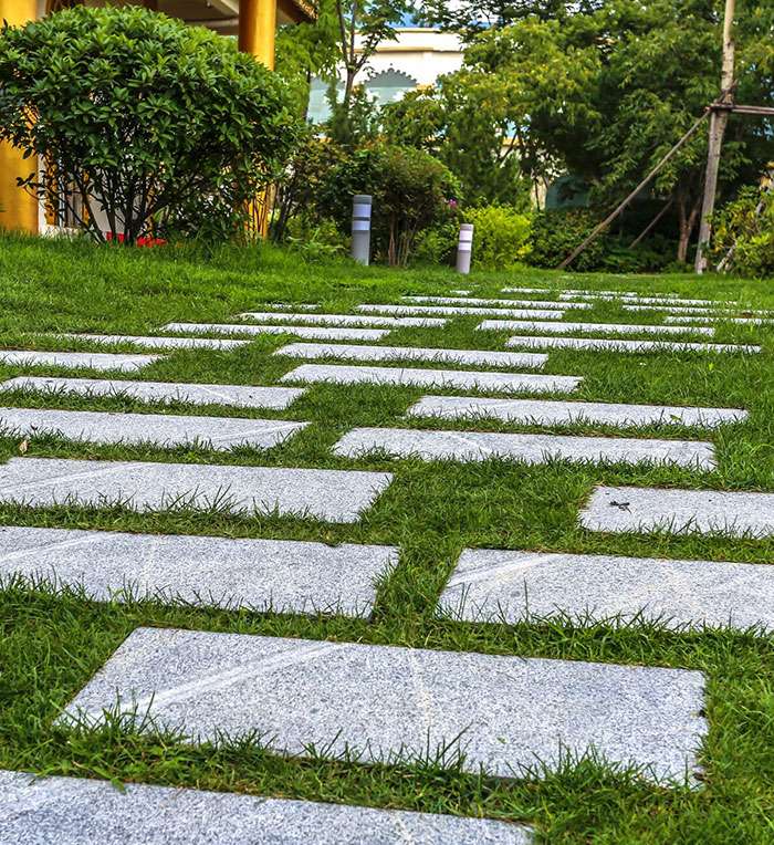 Garden pathway landscape design with stepping stone pavers set in grass and landscaped borders