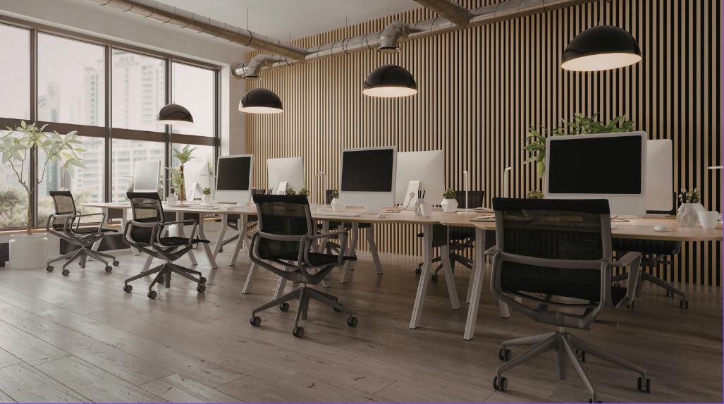 “Contemporary open-plan office with shared workstations, ergonomic chairs, desktop computers, pendant lighting, wood flooring, and a slatted feature wall.”