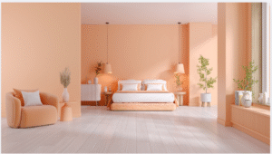 A serene, minimalist bedroom in warm peach tones featuring a low-profile bed with layered bedding, soft ambient lighting, a curved lounge chair, indoor plants, and large windows with natural light.