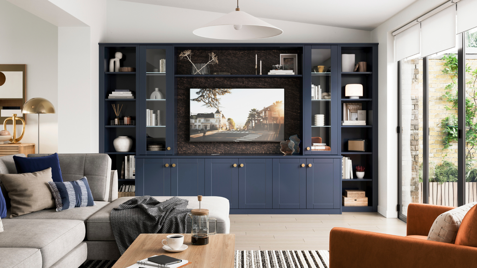 “Modern living room with a bespoke navy blue built-in media unit, open shelving, neutral sofa, wooden flooring, and large windows bringing in natural light.”