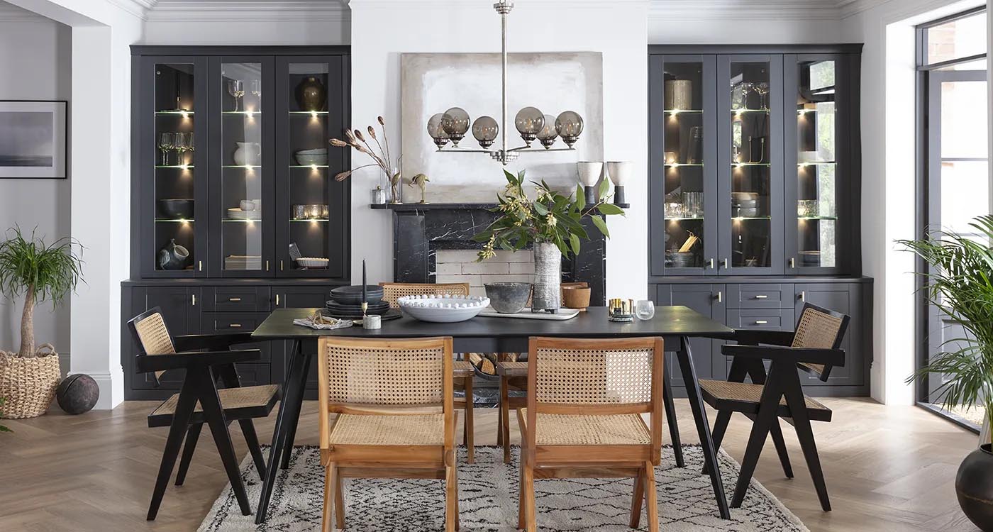 “Elegant open-plan dining room with a black dining table, mixed seating, glass-front cabinetry, pendant lighting, and indoor plants creating a bright, modern atmosphere.”
