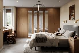 “Modern bedroom interior with warm wood-finished wardrobes, upholstered bed, soft neutral bedding, pendant lighting, and a calm, minimalist layout.”