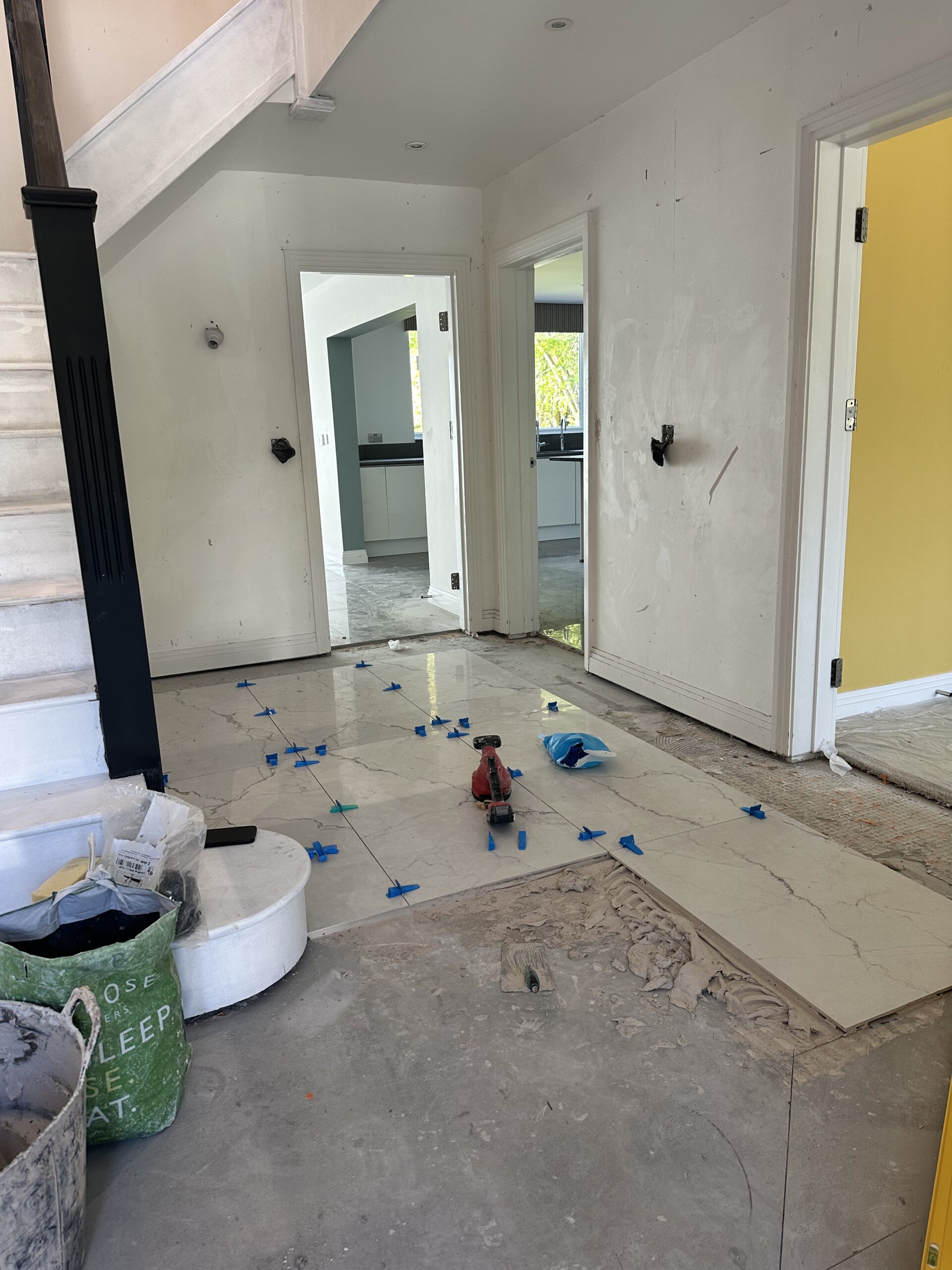 Luxury Bedroom Renovation and Wall Paneling Installation A bedroom under renovation showing a grey feature wall with decorative molding and a marble-patterned accent panel, with furniture covered in protective plastic.
