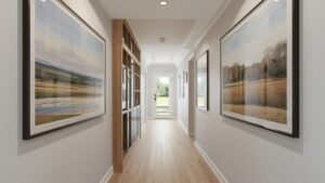 Modern hallway with framed landscape paintings, light wood flooring, built-in wooden cabinetry, and glass door at the end letting in natural light.