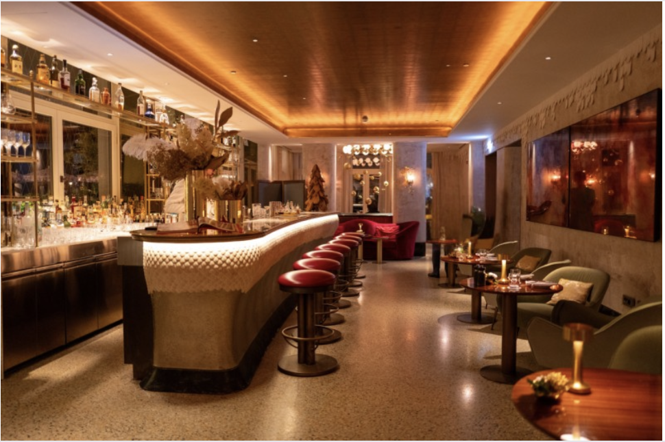 Contemporary Cocktail Bar Interior with Curved Counter Sophisticated cocktail bar interior showcasing a curved bar counter, leather stools and warm ceiling lighting for an upscale guest experience.