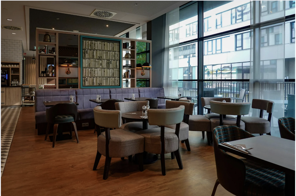 Contemporary Café Bar Interior Design Bright café bar interior featuring upholstered seating, natural light and modern shelving for stylish hospitality environments.