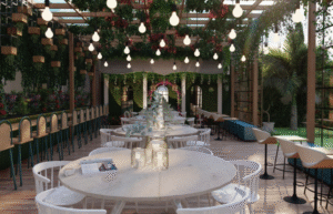 Garden-style restaurant terrace with hanging lights, lush greenery, and elegant outdoor seating.