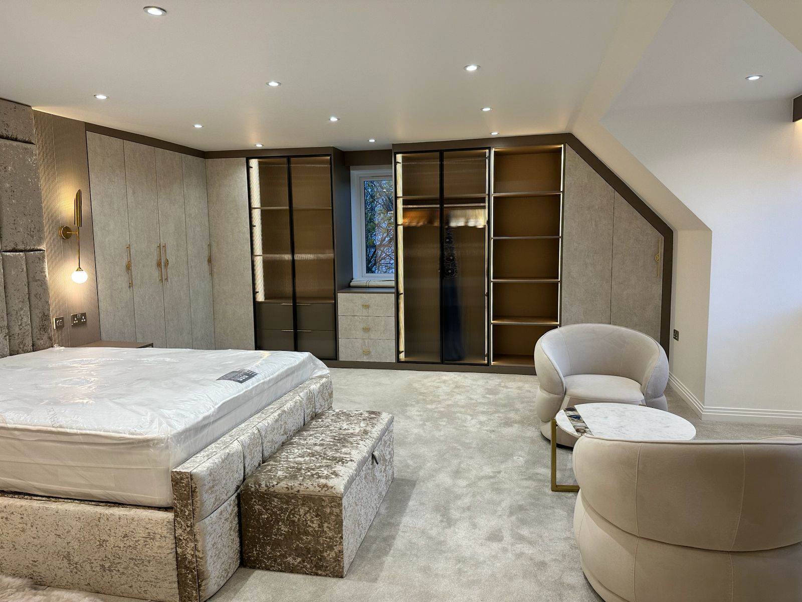Complete bespoke bedroom furniture installation including custom wardrobes, seating area and soft furnishings, designed for comfort and functionality.