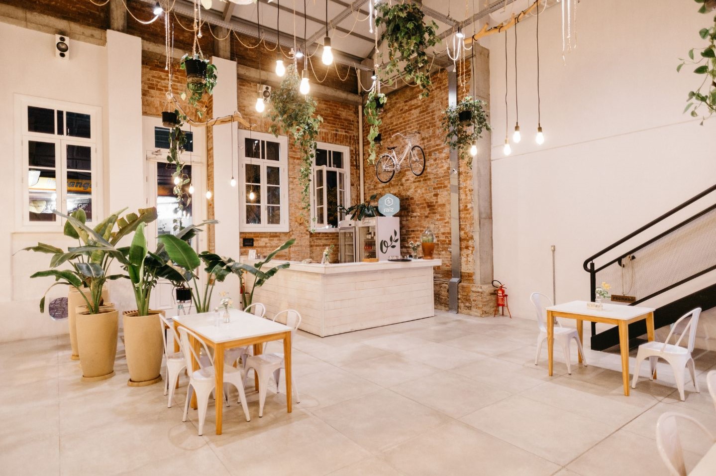 A restaurant layout by Oraanj Interior Design in London, UK includes a stylish space with brilliant seating elements alongside greenery features and a distinctive crystal chandelier.